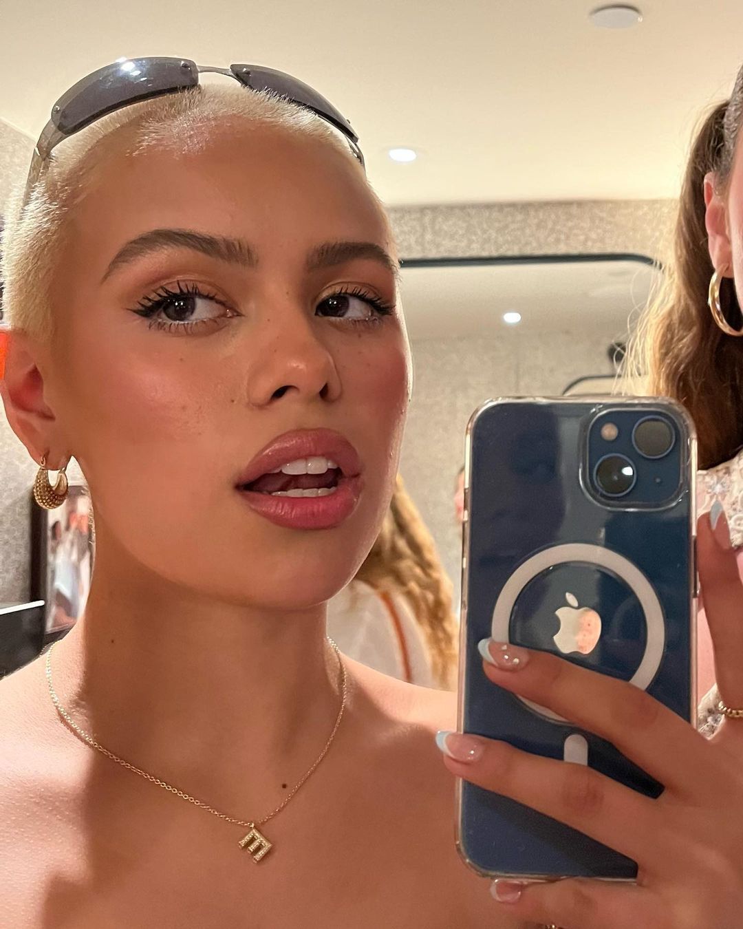 Woman with a blonde buzzcut taking a mirror selfie.