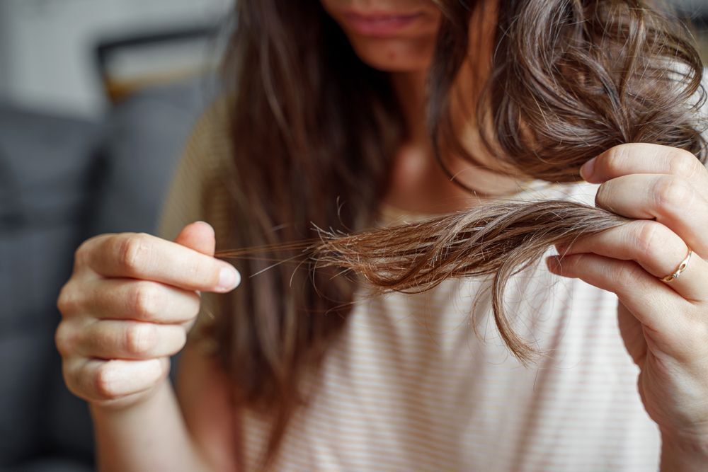 Woman pulling out fallen strands from her hair.