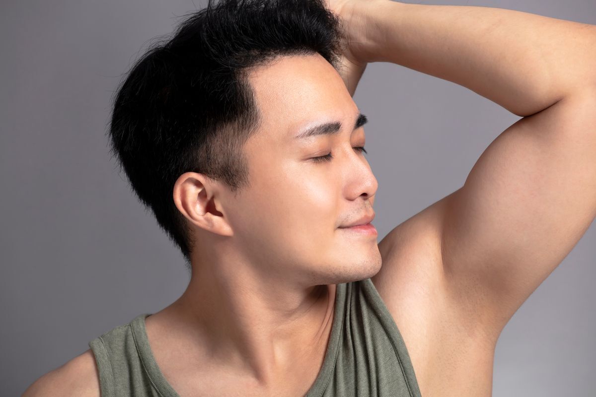 Asian man smelling armpits