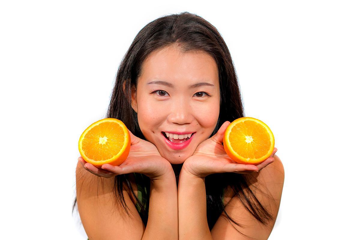 Asian woman holding oranges