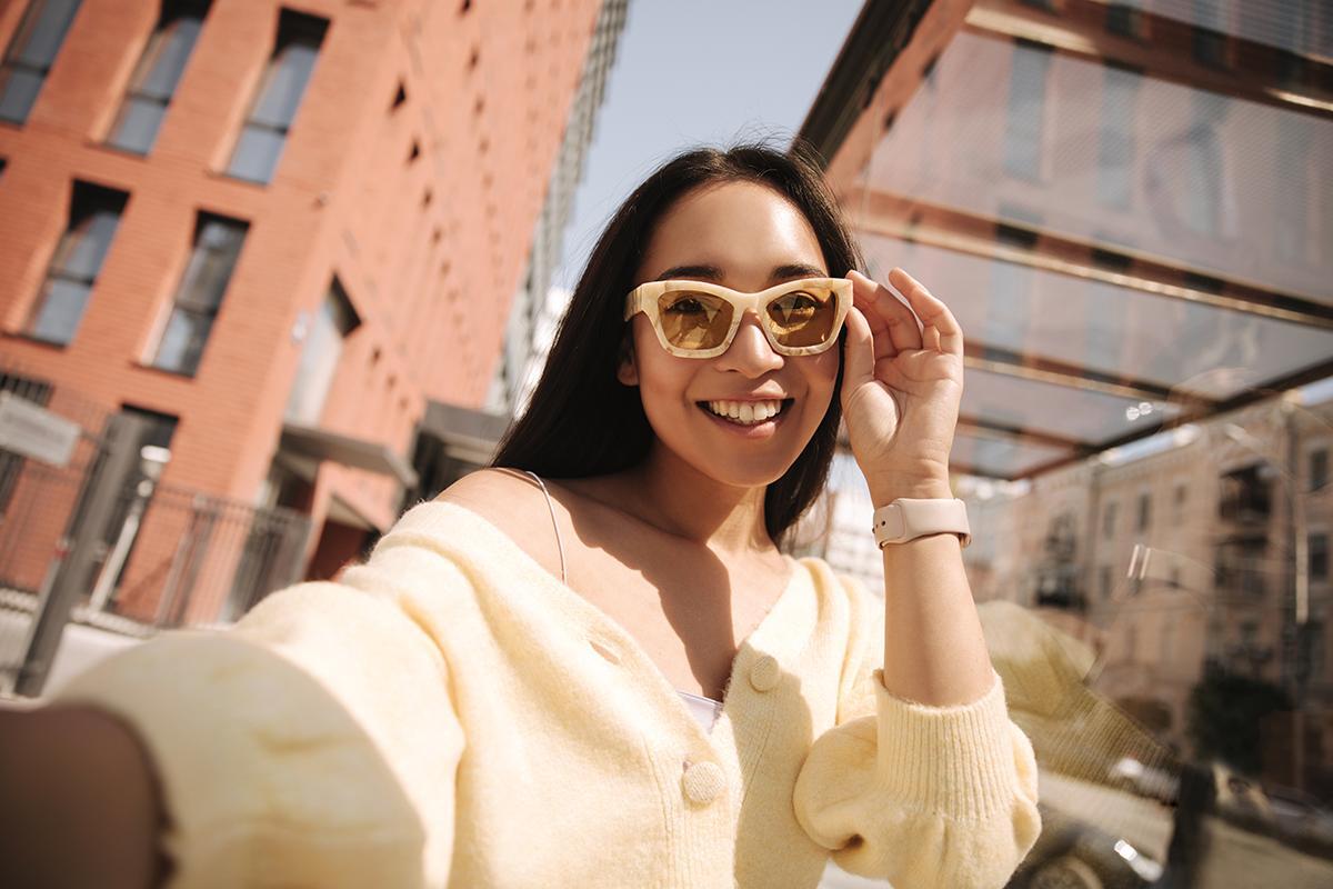 Asian woman outdoors holding sunglasses