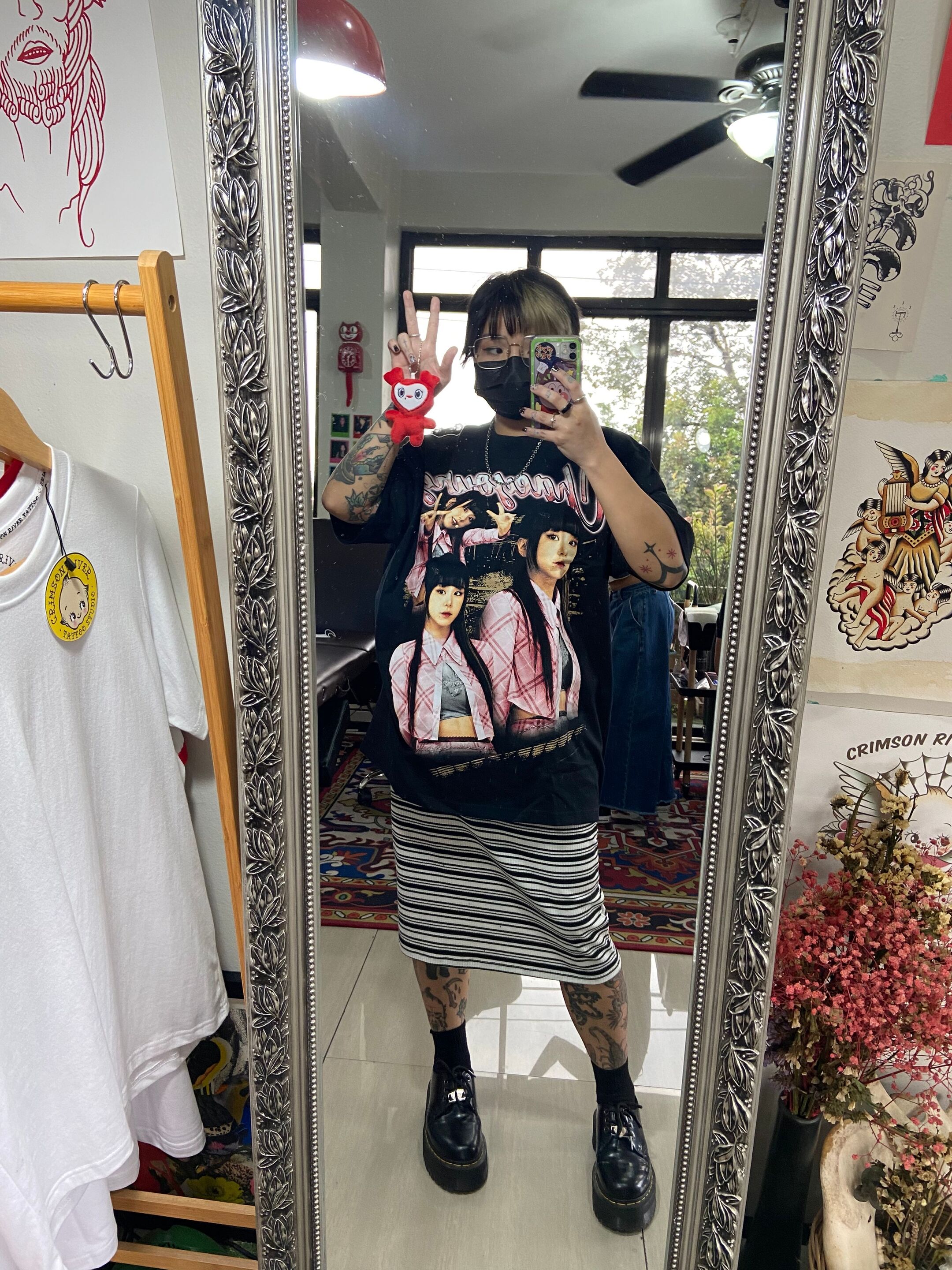 Woman wearing edgy clothes and colored hair taking a mirror selfie. 