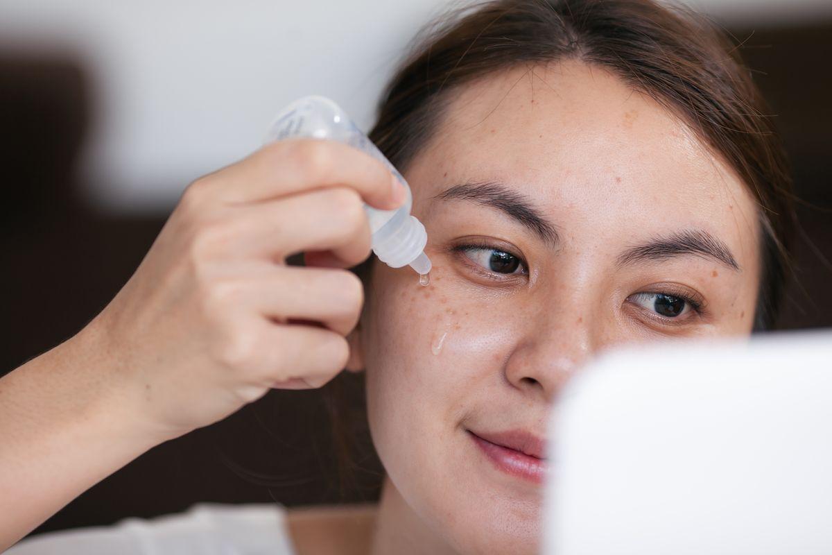 Asian woman applying serum closeup.