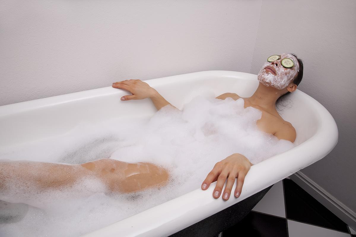 A woman in a bubble bath, with a facial