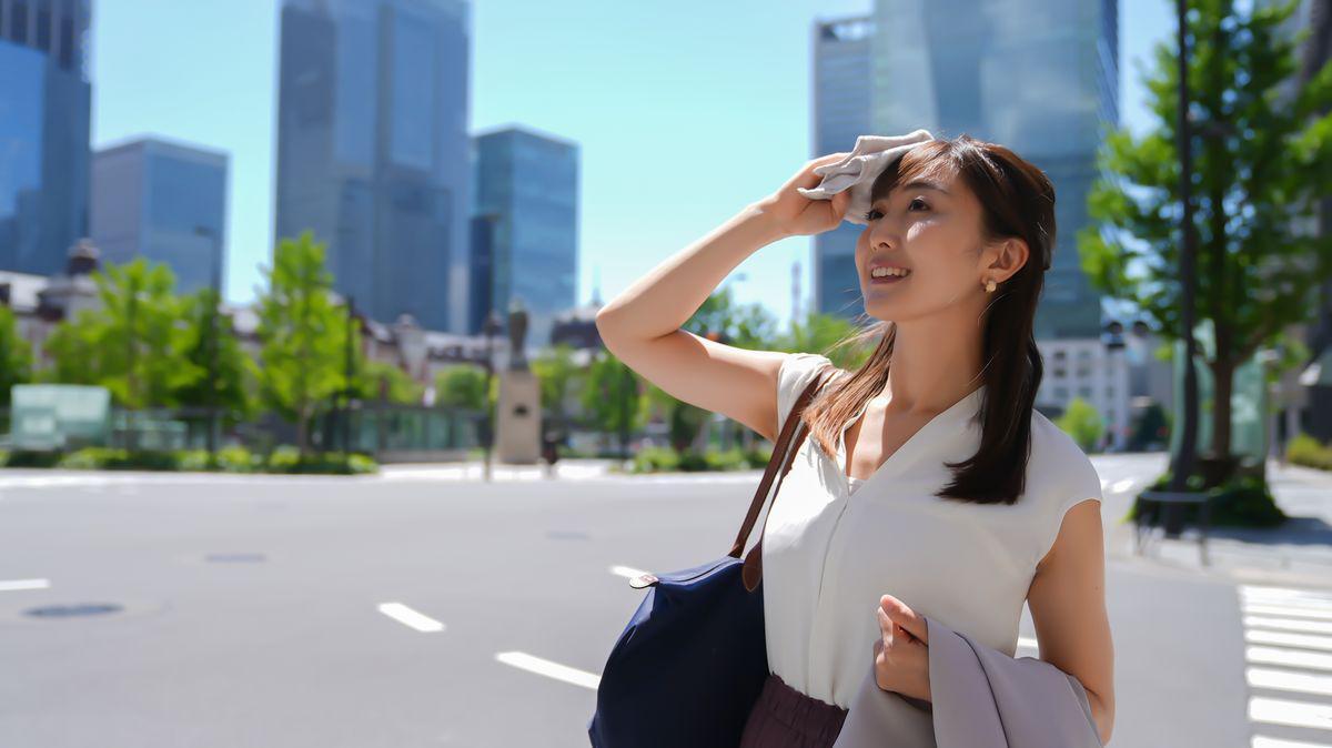 Asian businesswoman wiping sweat under the sun