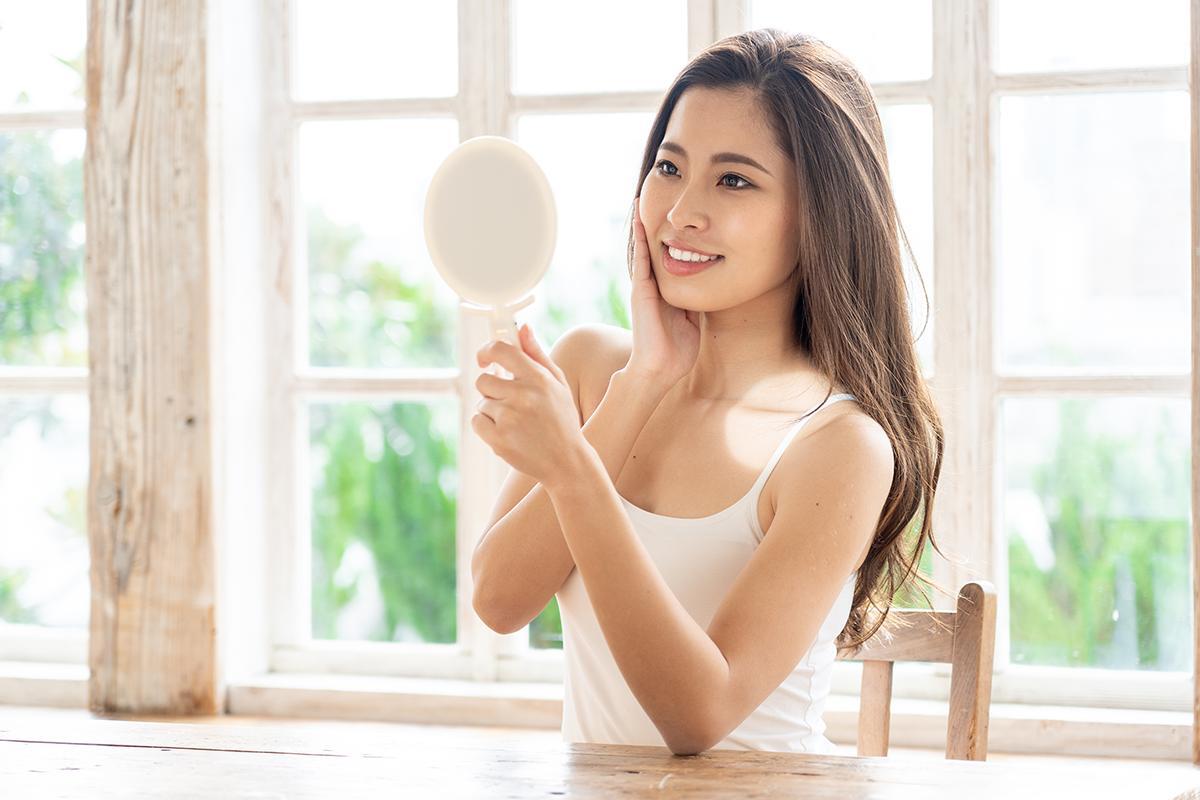 Asian woman looking at herself in mirror