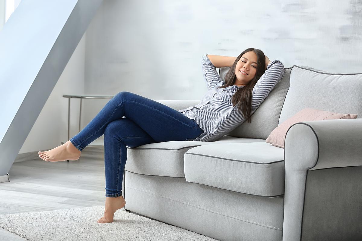 Asian woman relaxing on gray couch