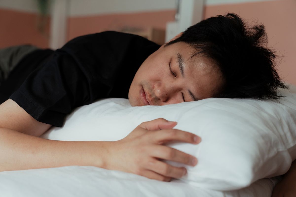 Young Asian male sleeps with his head on a pillow. 