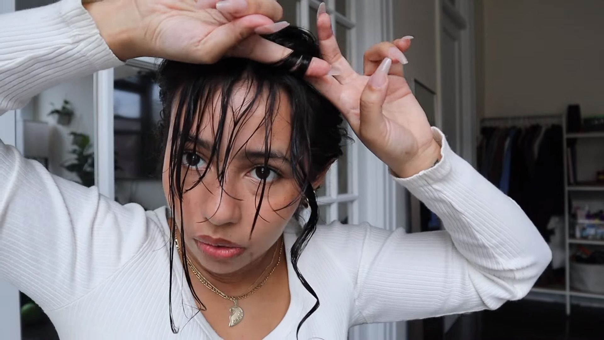 Woman doing the finger coil on her wet curly bangs.