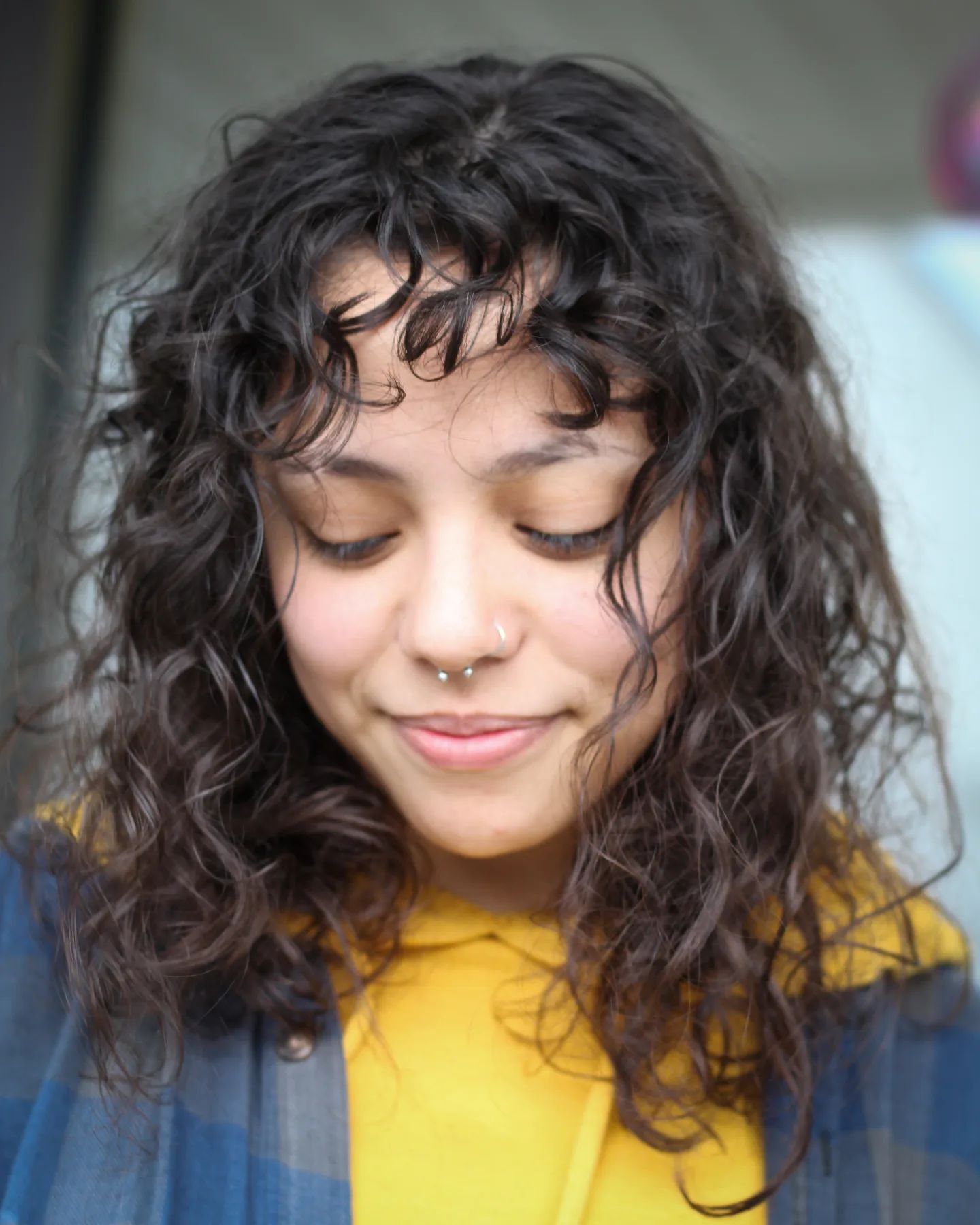 Woman with shoulder-length curly hair and curtain bangs. 