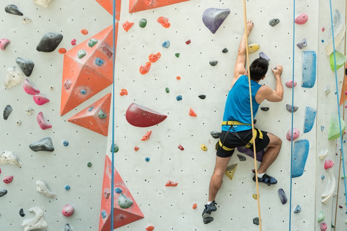 Asian man climbing an artificial rock wall.