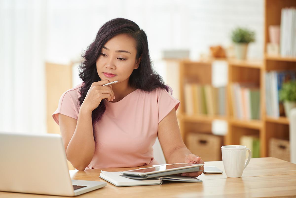 Asian woman in pink looking at laptop