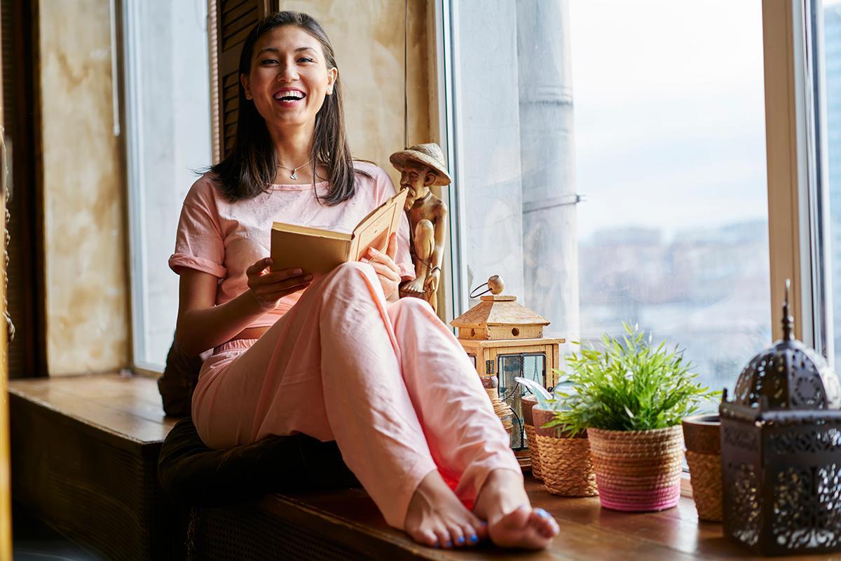 Asian woman reading by window