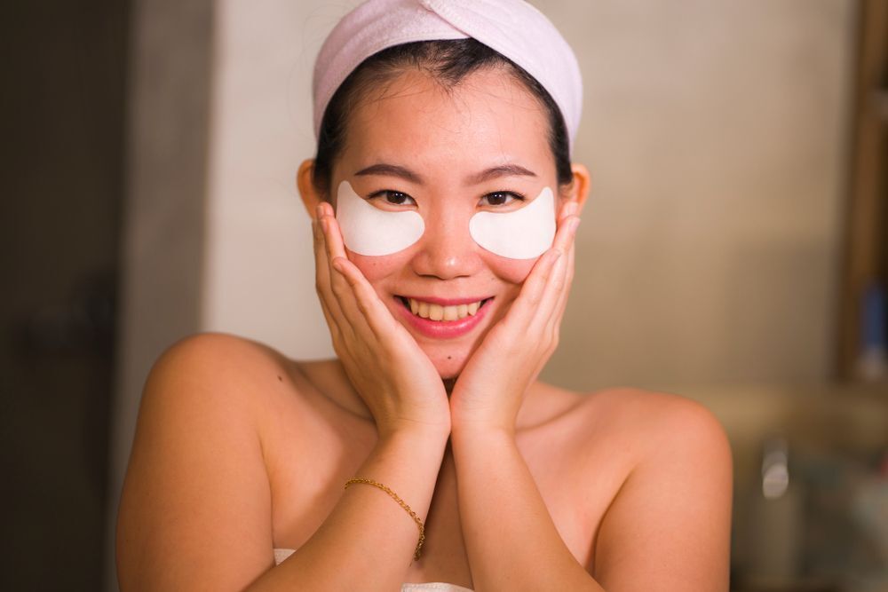 An Asian woman wearing eye patches touching her face