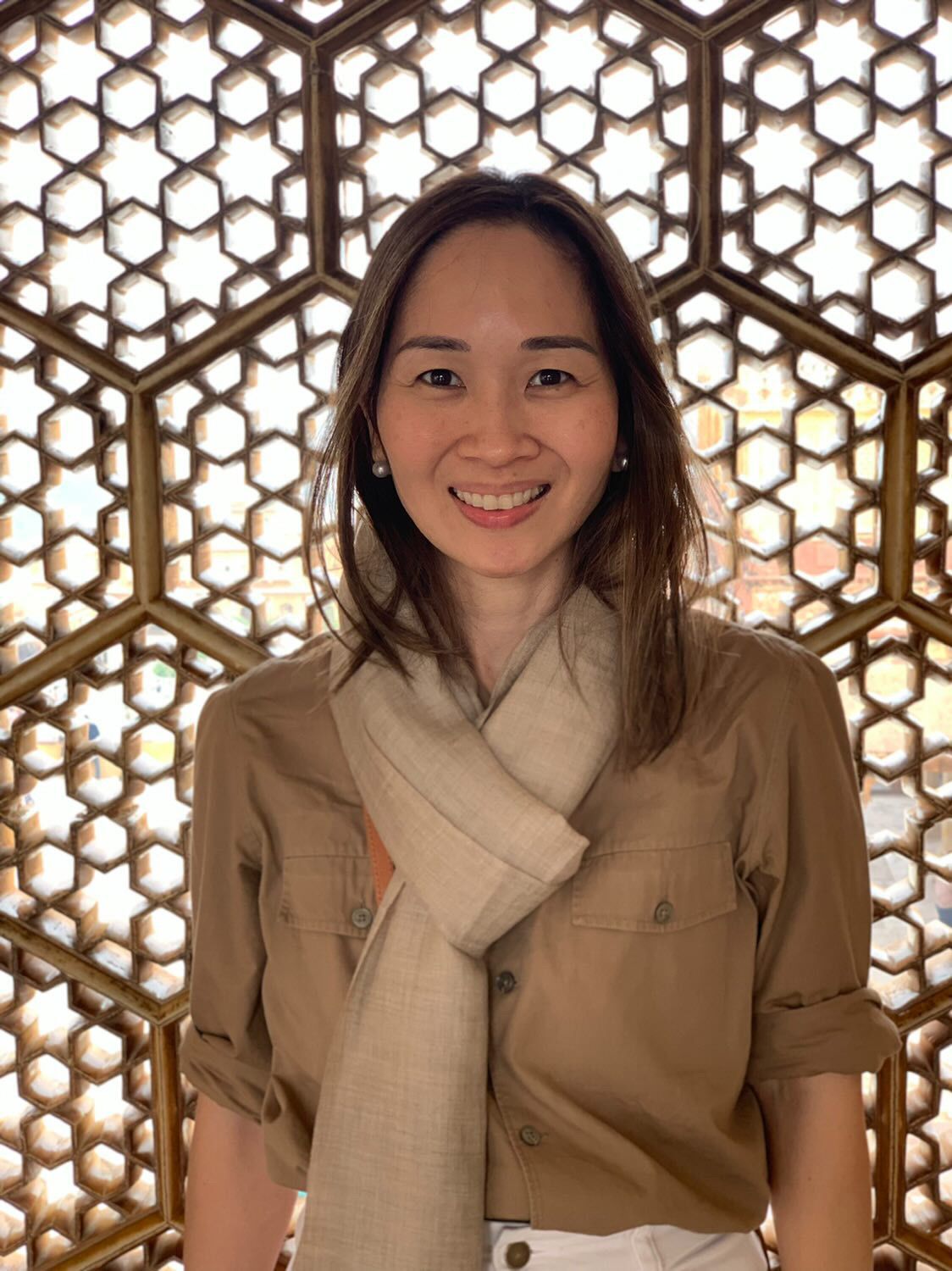 Smiling Asian woman wearing brown shirt and scarf.