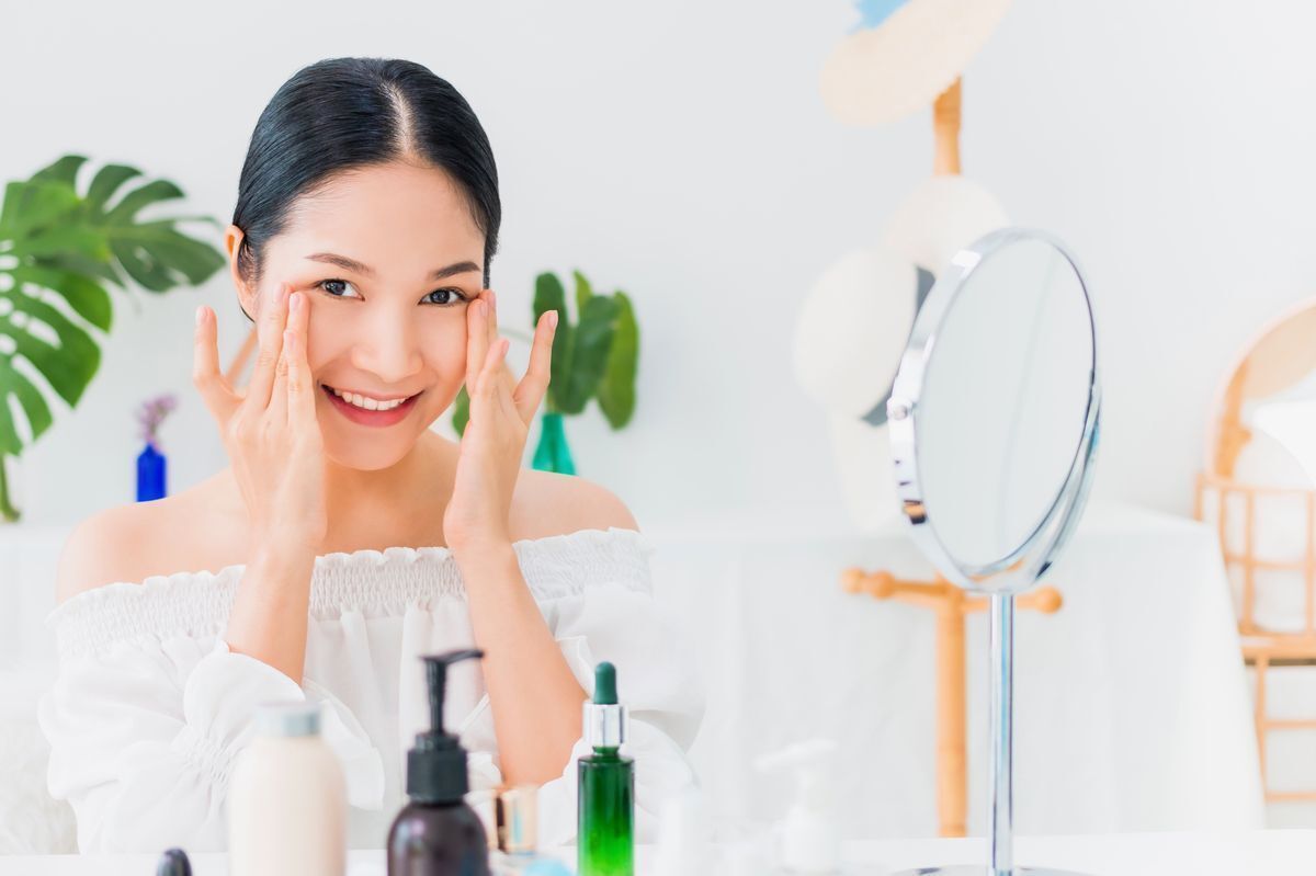 Woman applying her skincare product while smiling at the camera.
