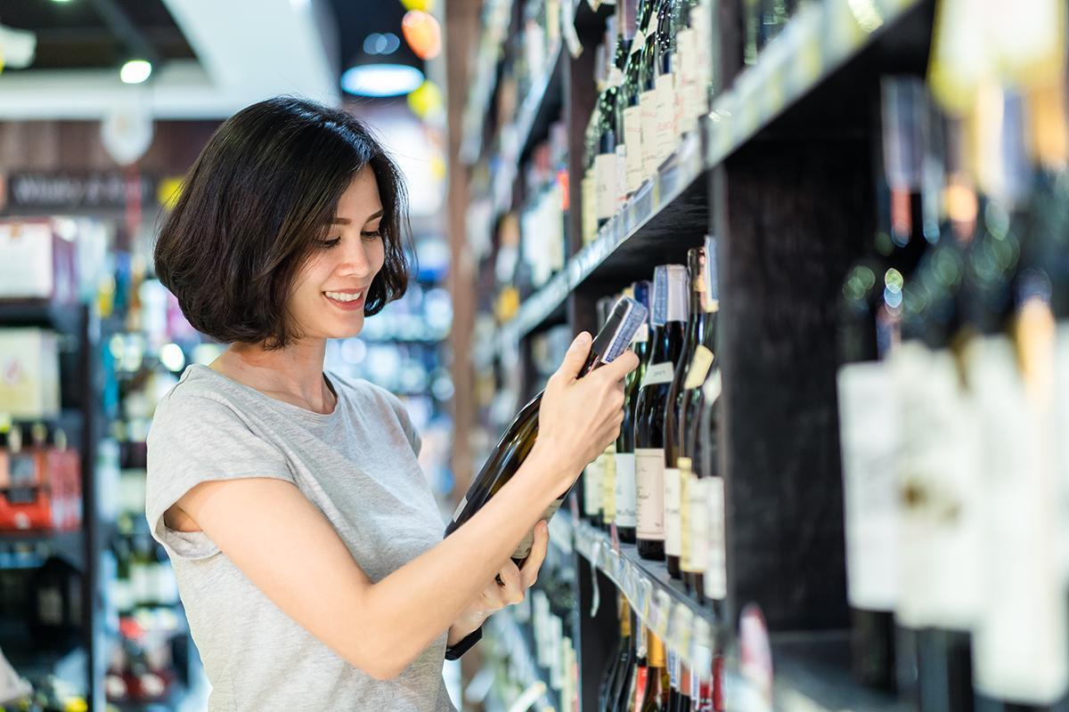 Asian woman choosing wine at a store