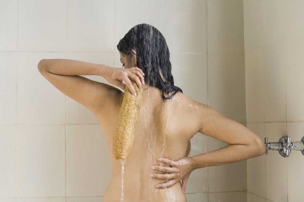 Woman using a loofah on back