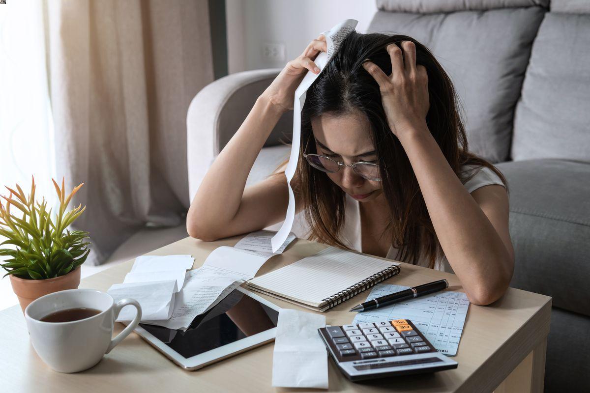 Stressed out young woman calculating bills 