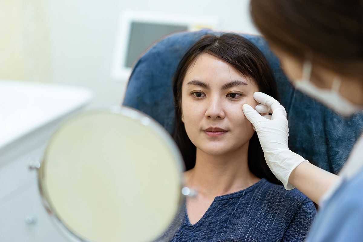 Asian woman looking in a mirror at a clinic