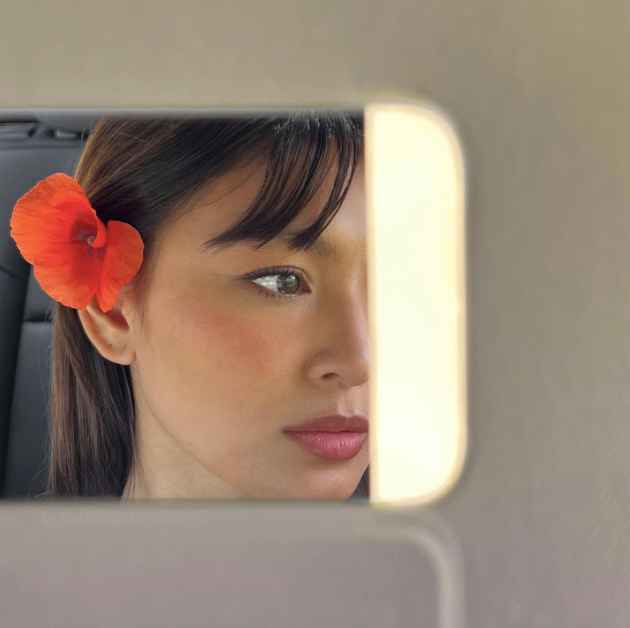 Nadine Lustre, with a flower in her ear, snaps a mirror selfie in the car.