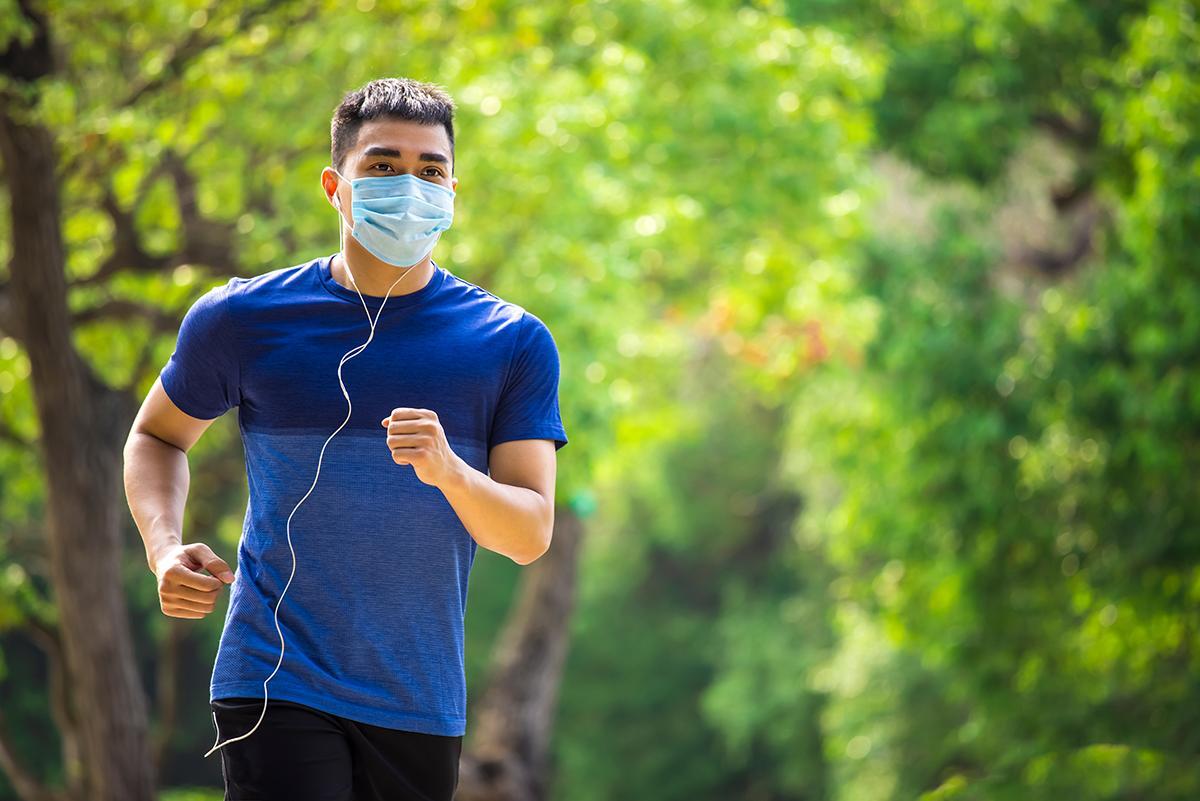 Asian man in blue wearing mask while jogging