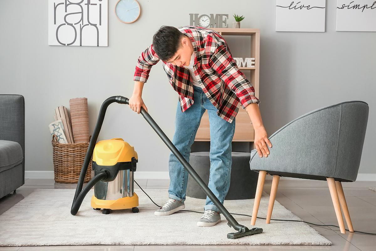 Asian man cleaning living room