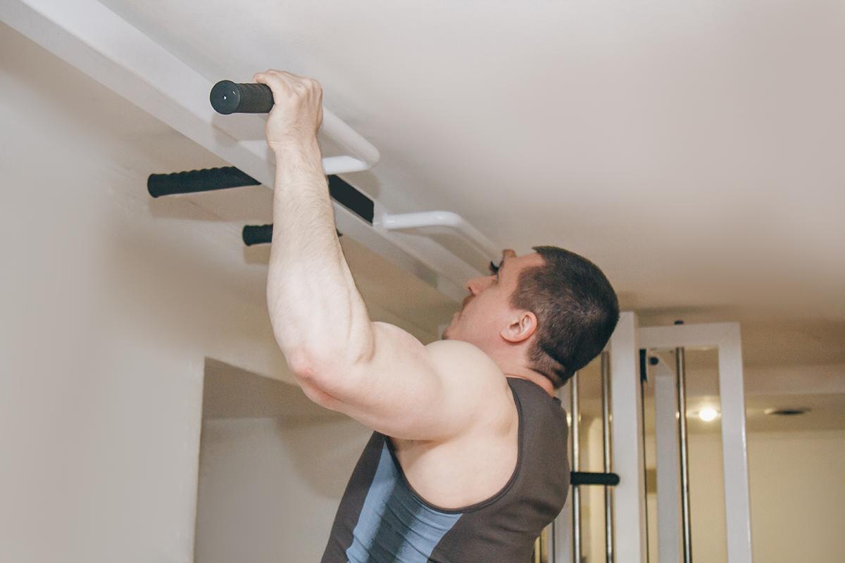 A man uses a pull up rack