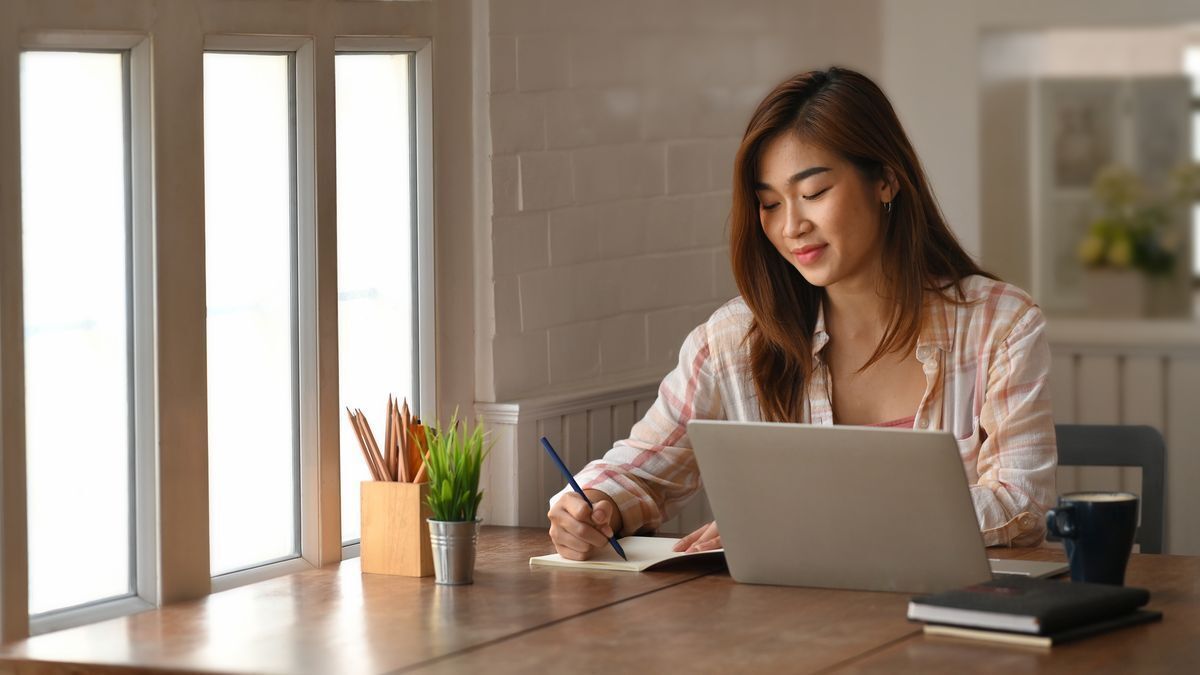 Filipino woman taking notes, with open laptop