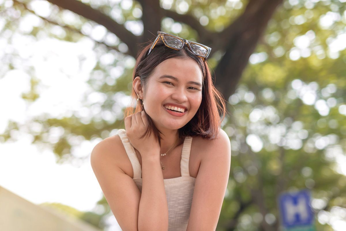 Filipino woman in white sleeveless top smiling outdoors