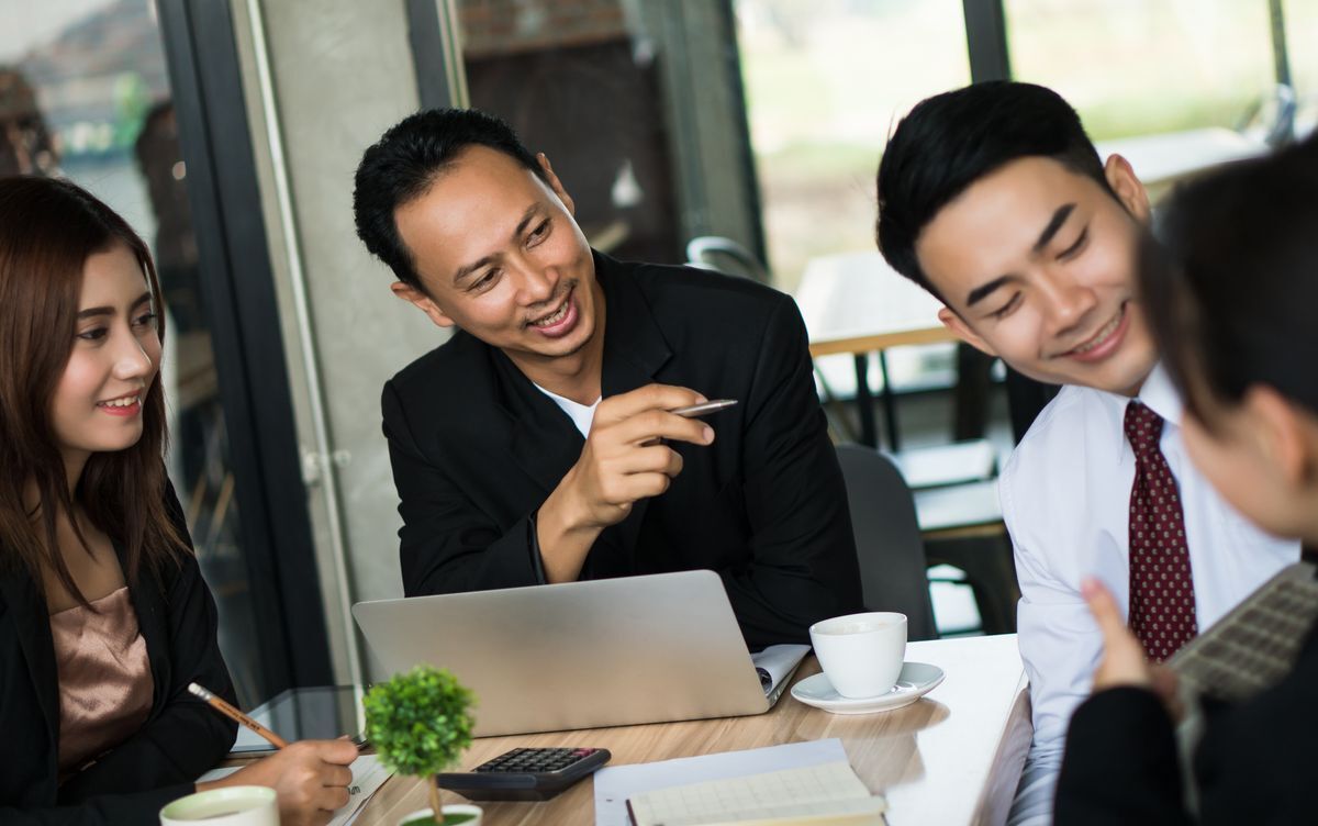 Asian man brainstorming with teammates.