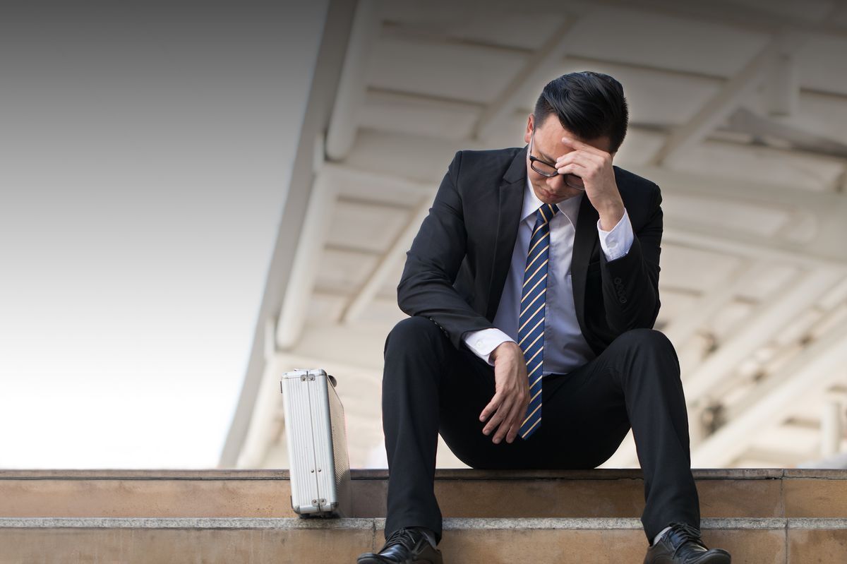 Filipino career man disappointed while sitting on concrete steps.