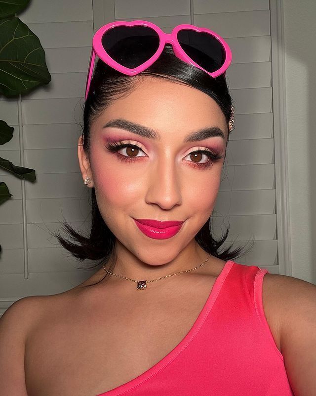 Woman with pink cut crease eye makeup and bold pink lips. 