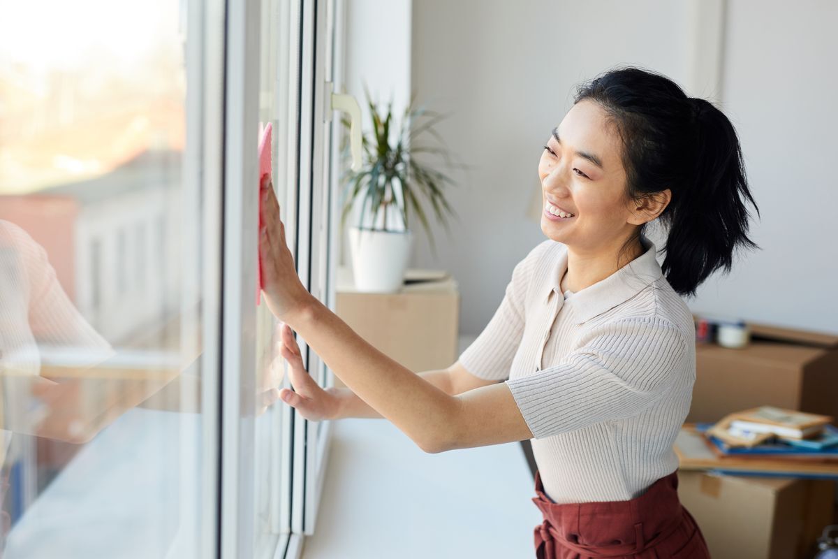 Asian woman wiping a window