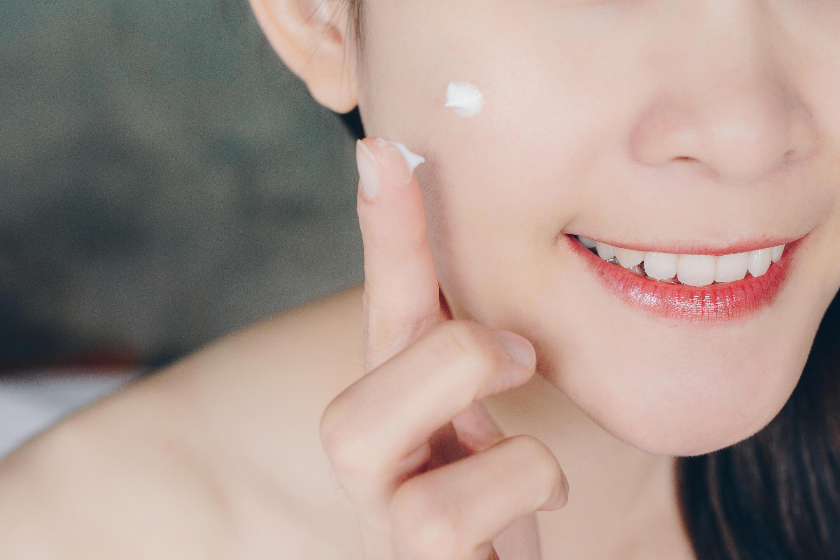 Closeup of Asian woman applying cream on her face