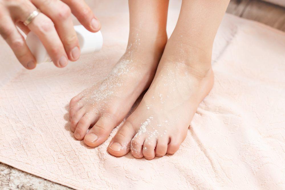 Woman applying deo powder to feet