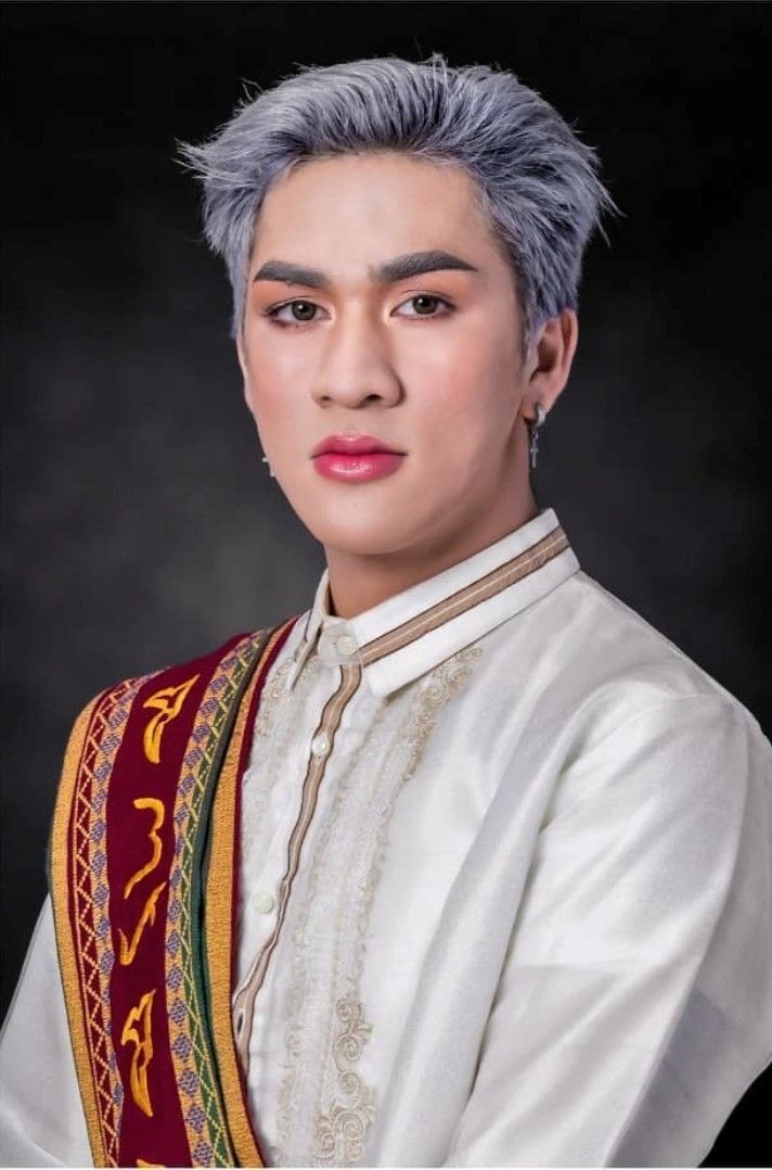 Graduation photo of a young man with silver hair, and wearing a sash