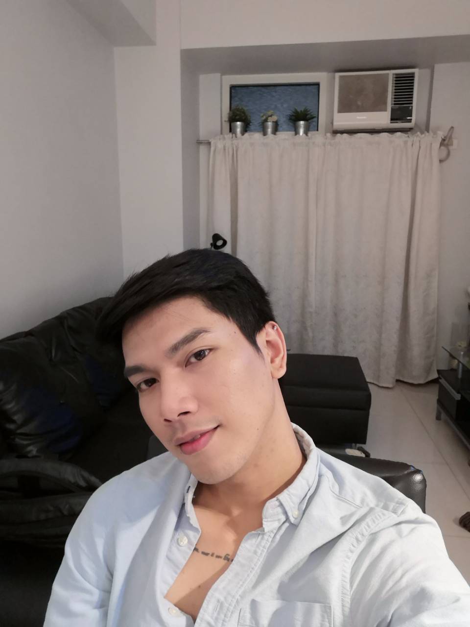 An Asian man with open collar taking a selfie