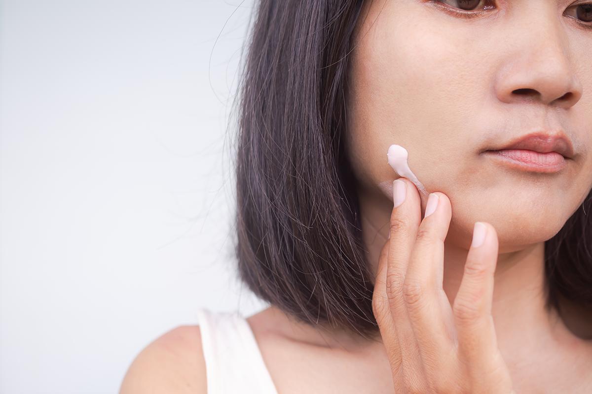 Woman applying cream on face