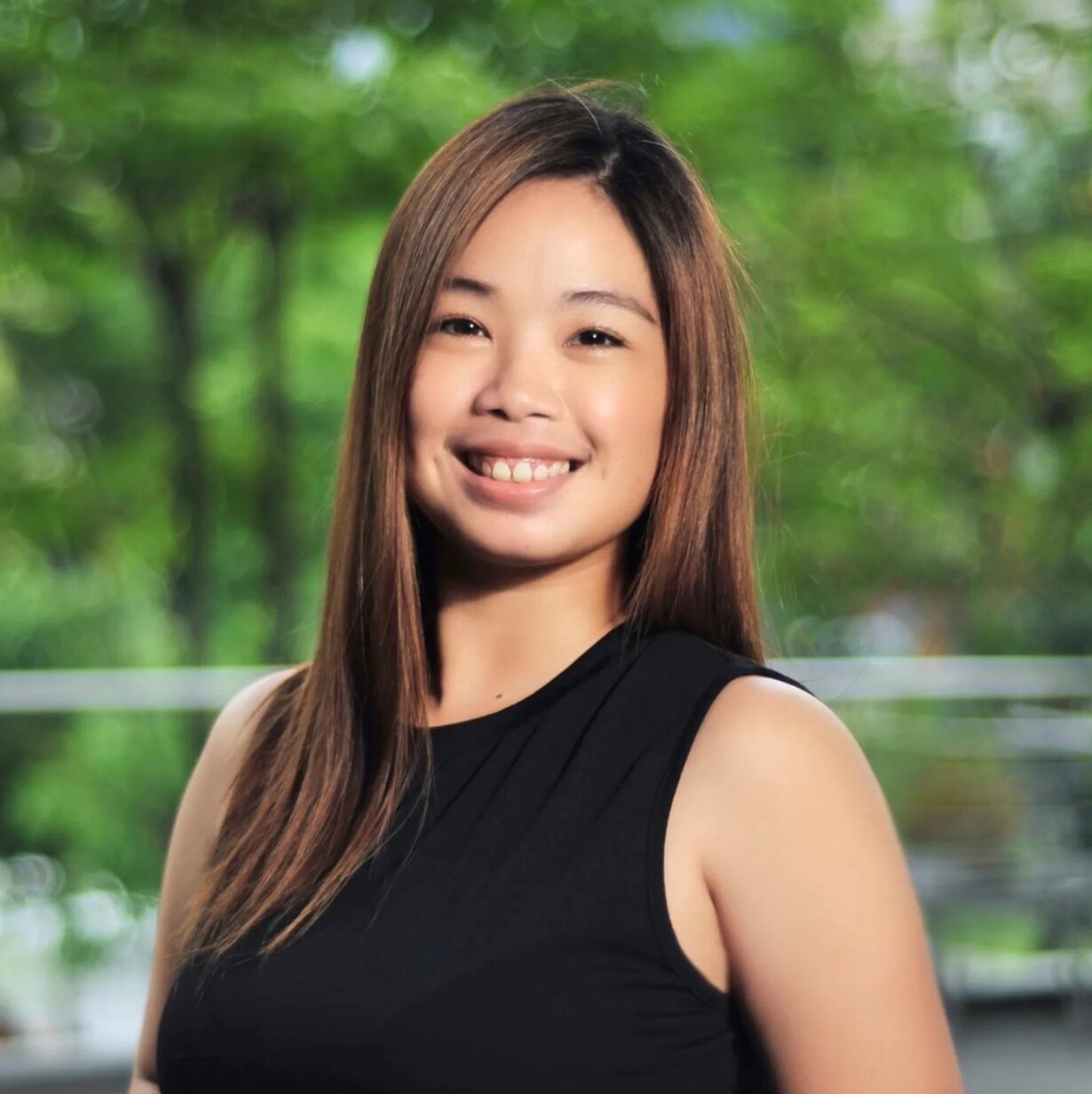 Portrait of Asian woman smiling against a background of greenery.
