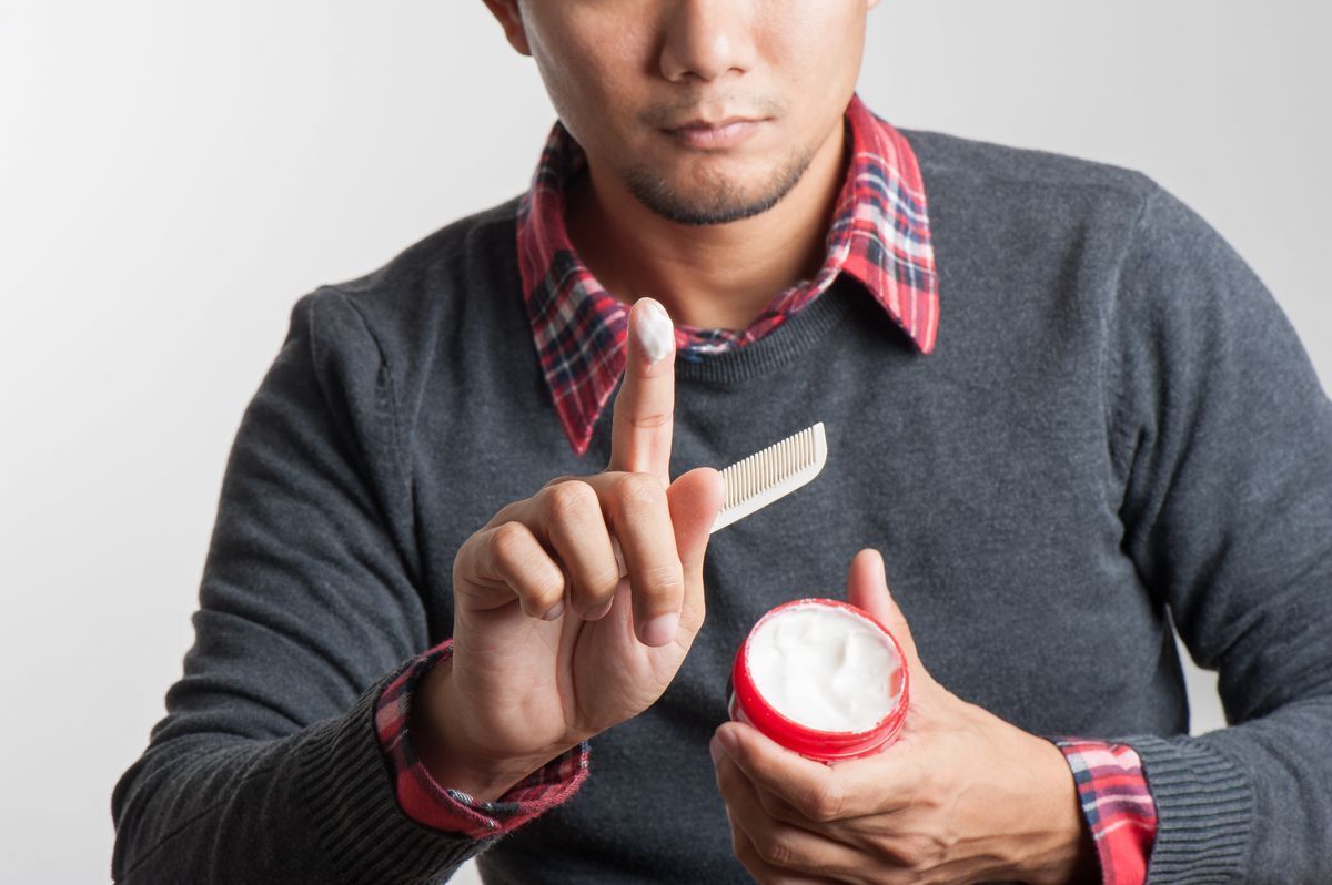 A man holds up a finger coated with pomade.