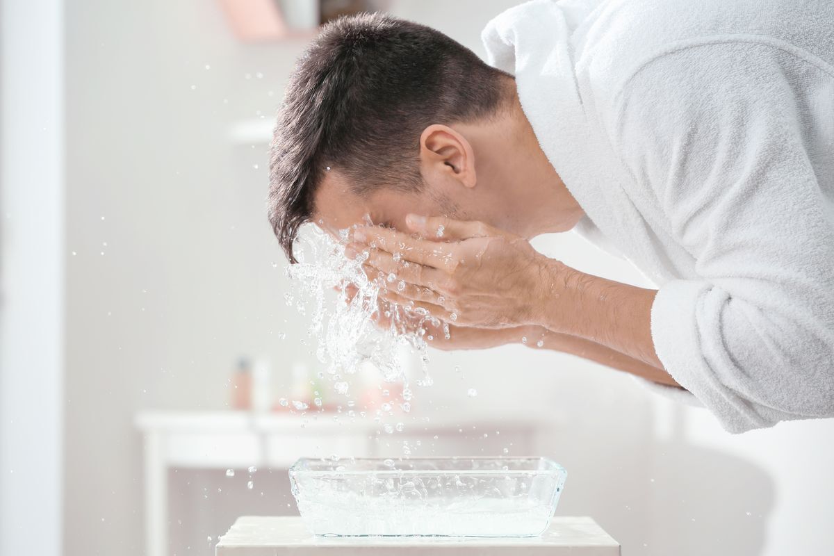 A man washing his face in a sink.