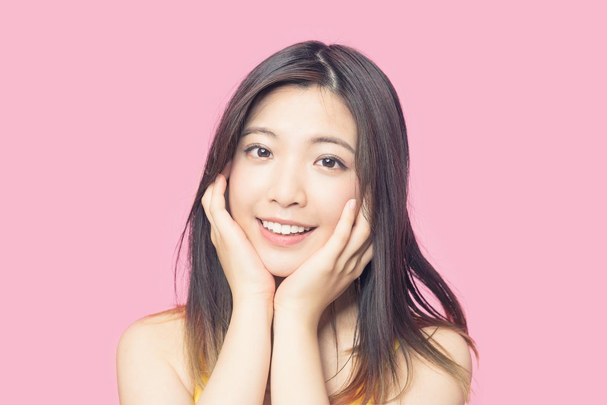 A woman with long hair and pink background.