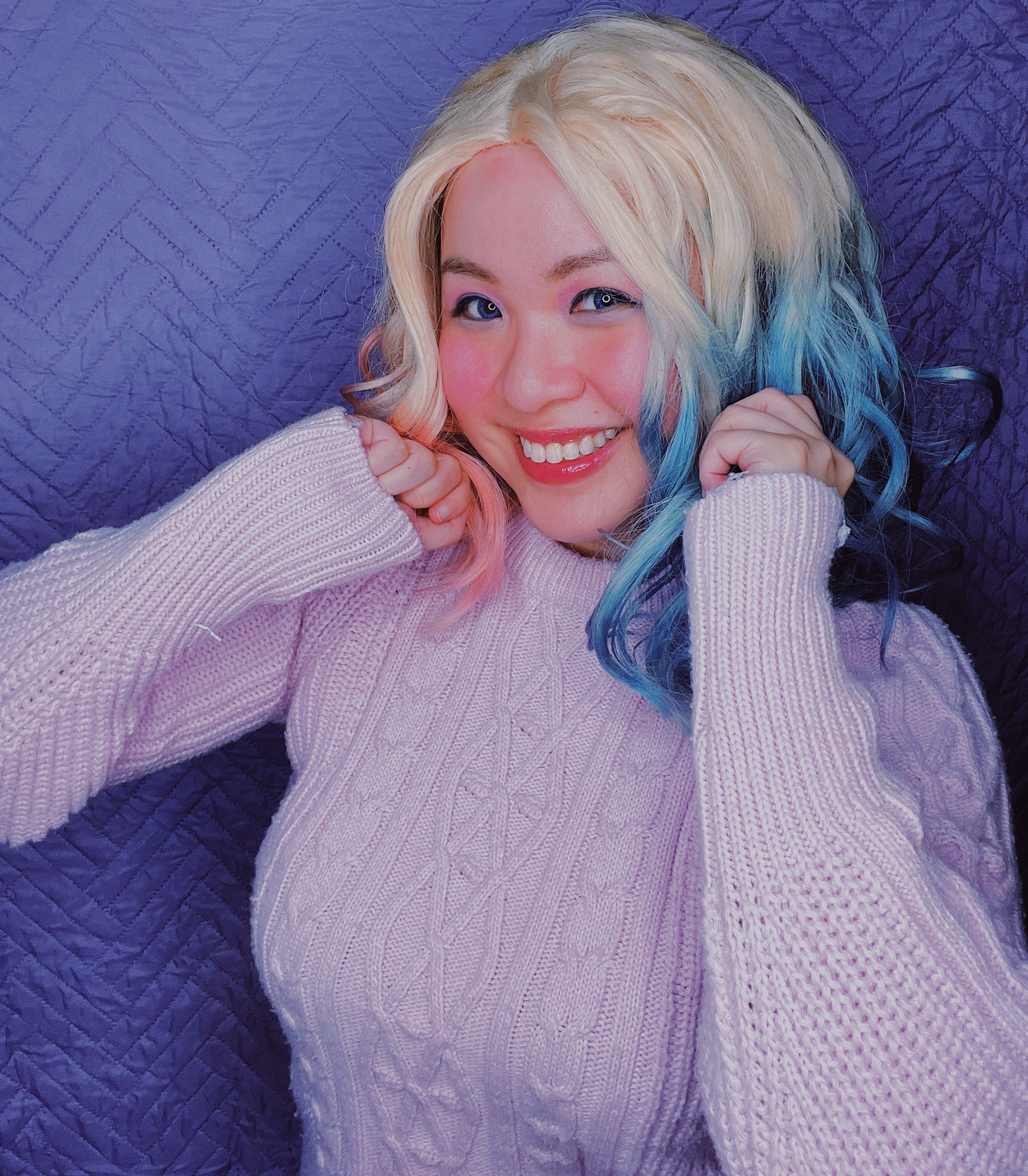 Woman with Harley Quinn-style wig and white sweater posing in front of the camera.