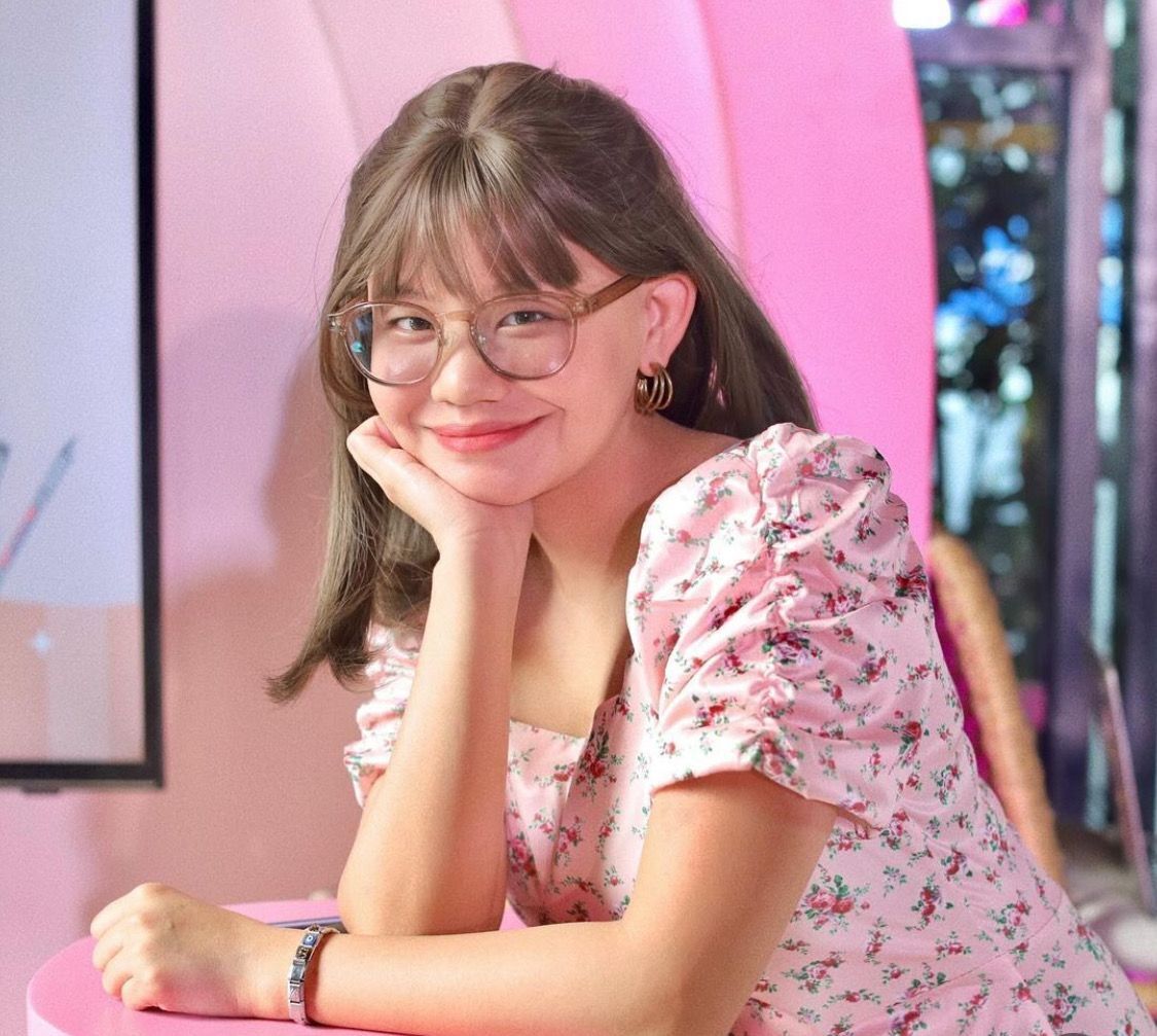 A portrait of woman with brown hair wig and pink dress.