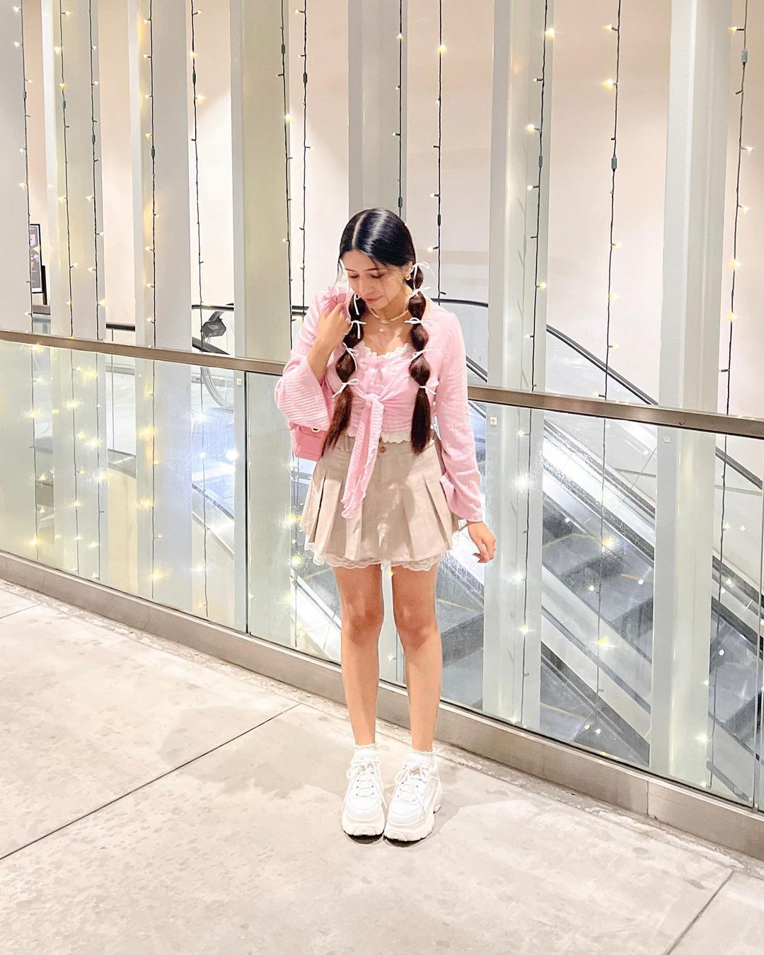 Woman wearing pink top, beige mini-skirt, and white sneakers.