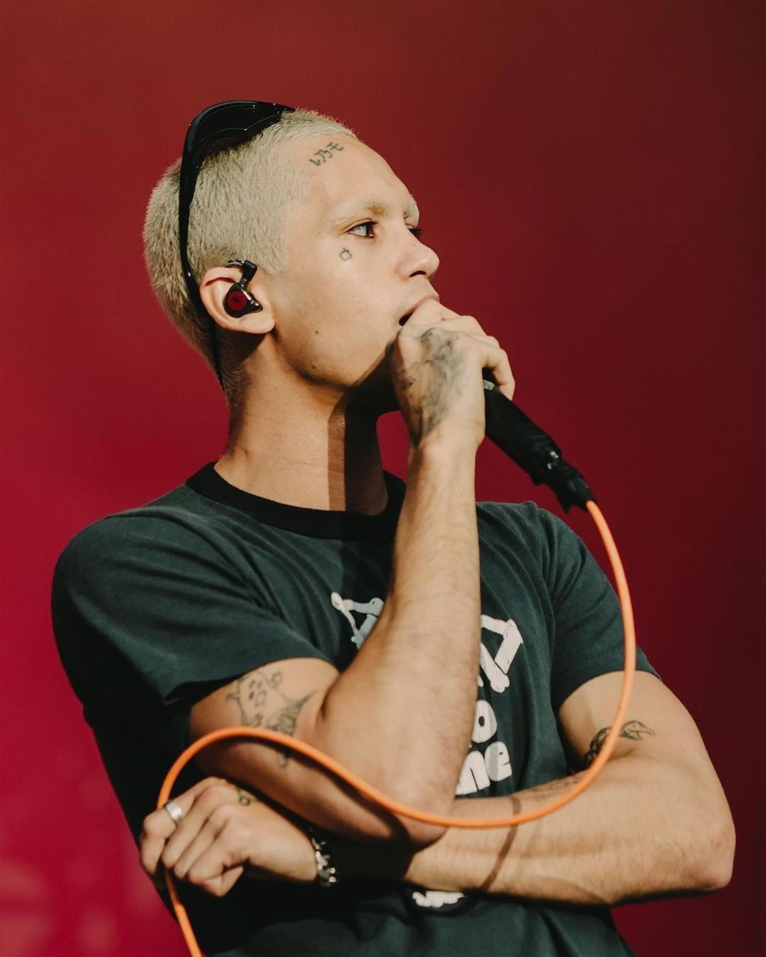 Dominic Fike with bleached buzz cut singing on stage.