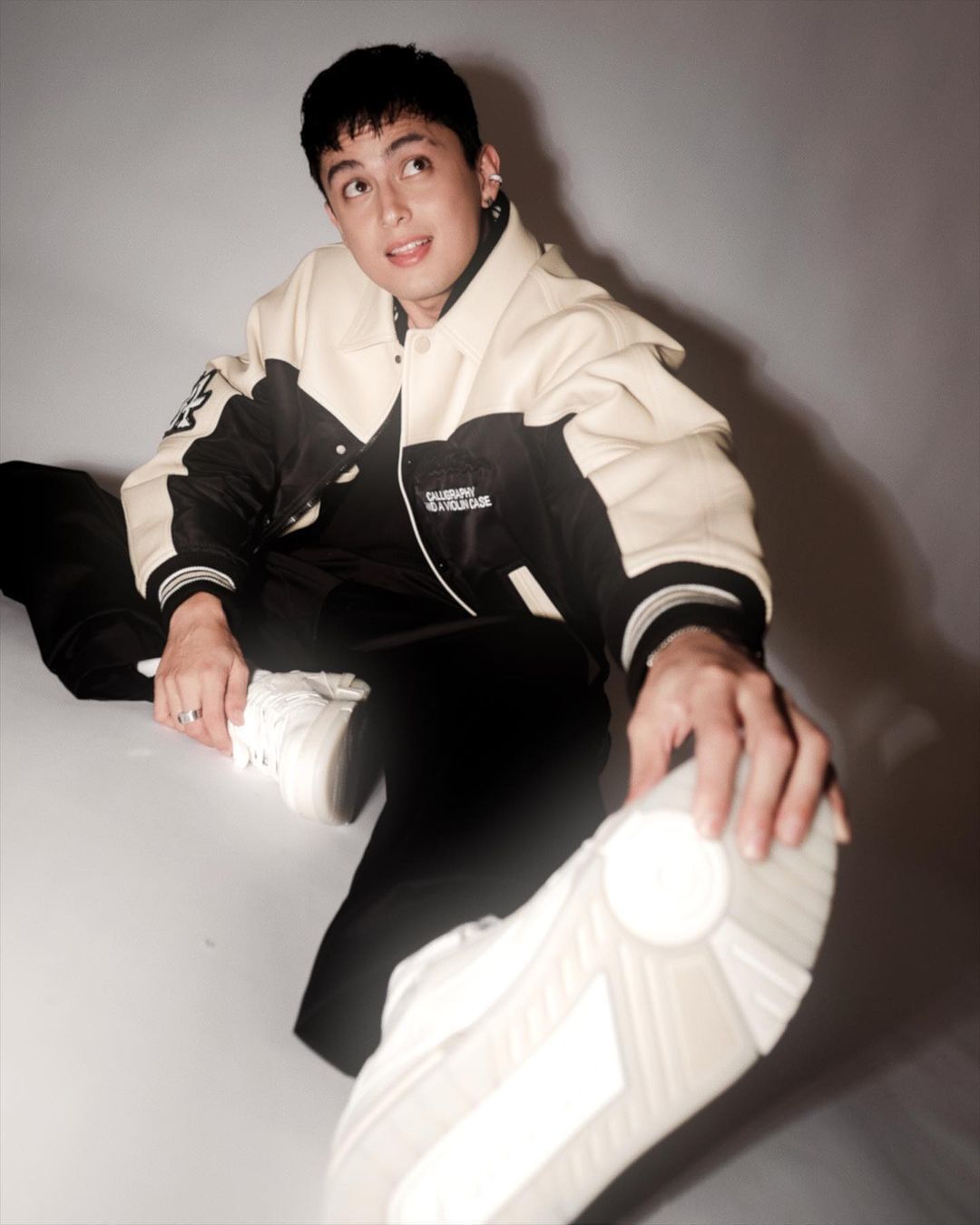 A portrait of James Reid with the Edgar haircut, sporty jacket, and white sneakers.
