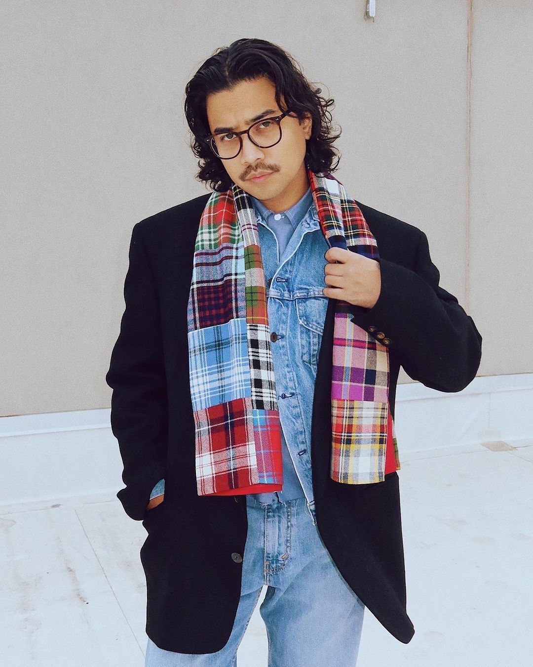 A portrait of man with long, wavy hair wearing layers of denim and a coat.