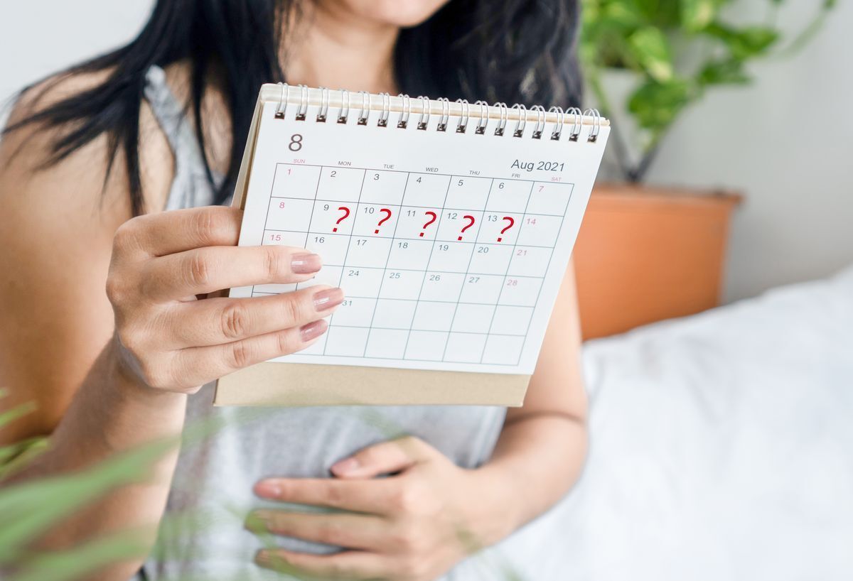 Woman holding a calendar with question marks in her hand.